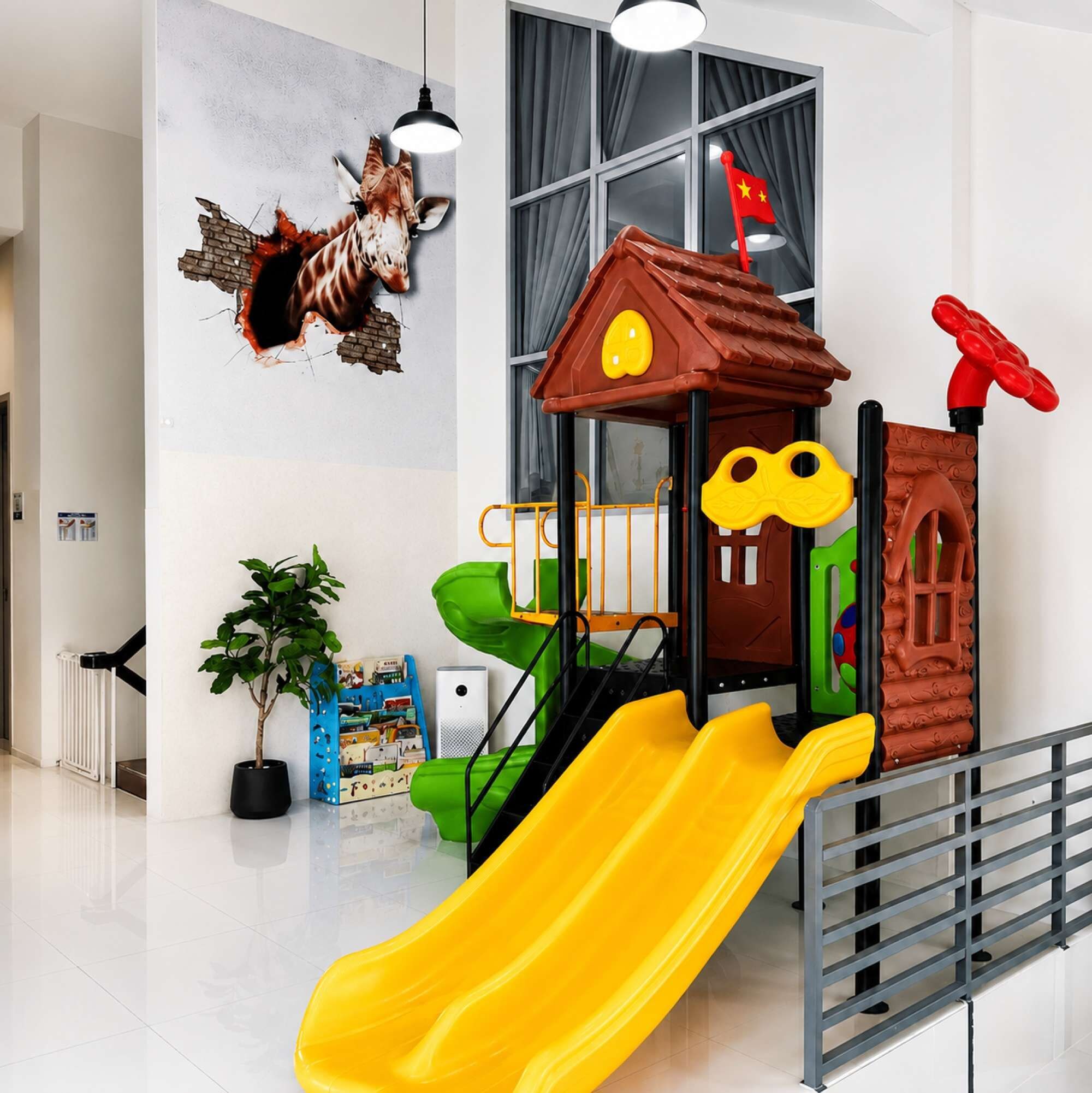 A children's play area with a slide, a playhouse, and a wall mural.