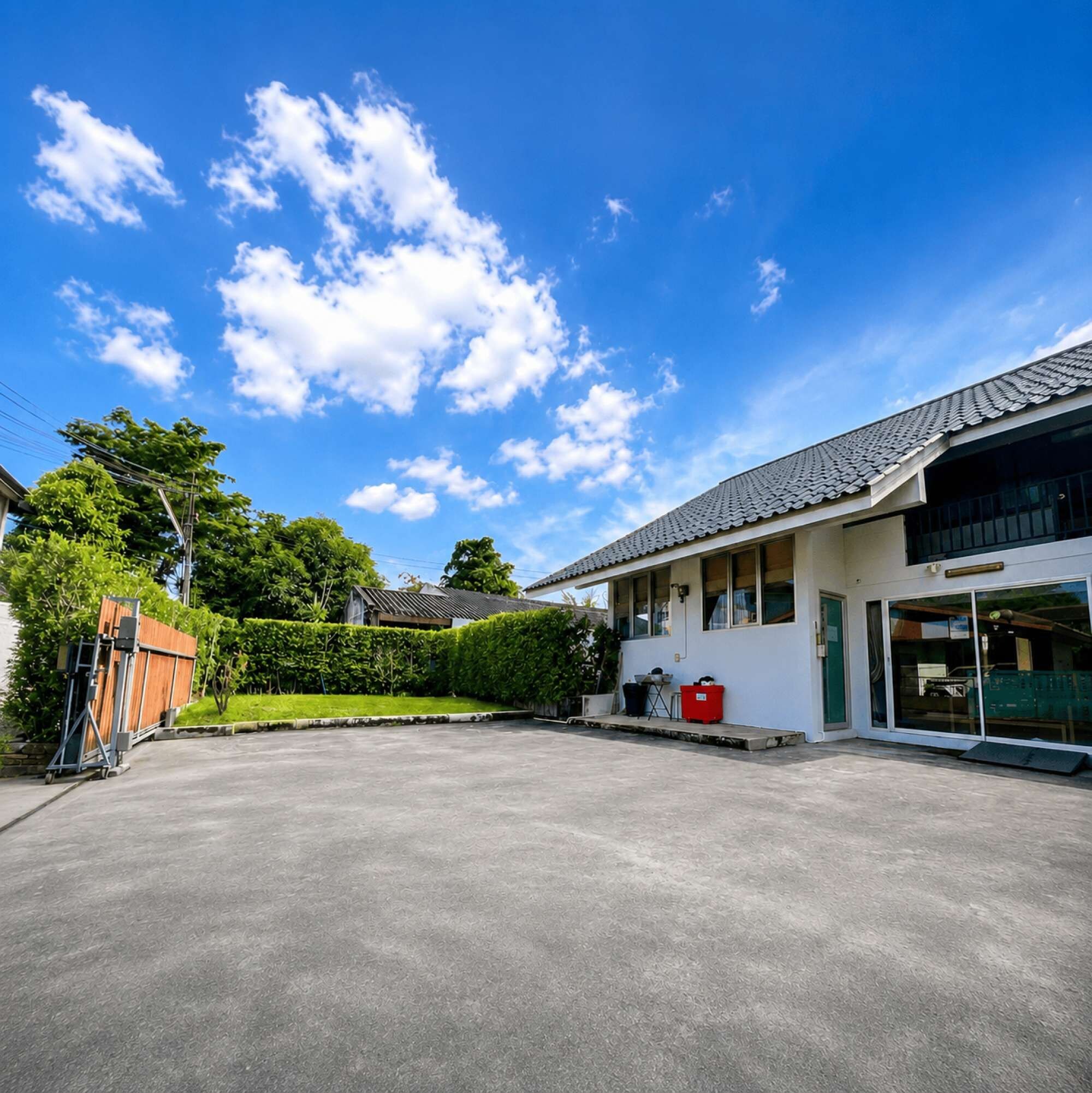 A spacious parking area with a building featuring a tiled roof and large windows.