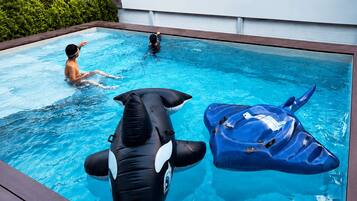Una piscina con juguetes inflables de orca y raya, y un letrero que dice 'Njoy Pool Villa'.