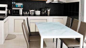 A modern kitchen with a marble dining table, built-in appliances, and a black backsplash.