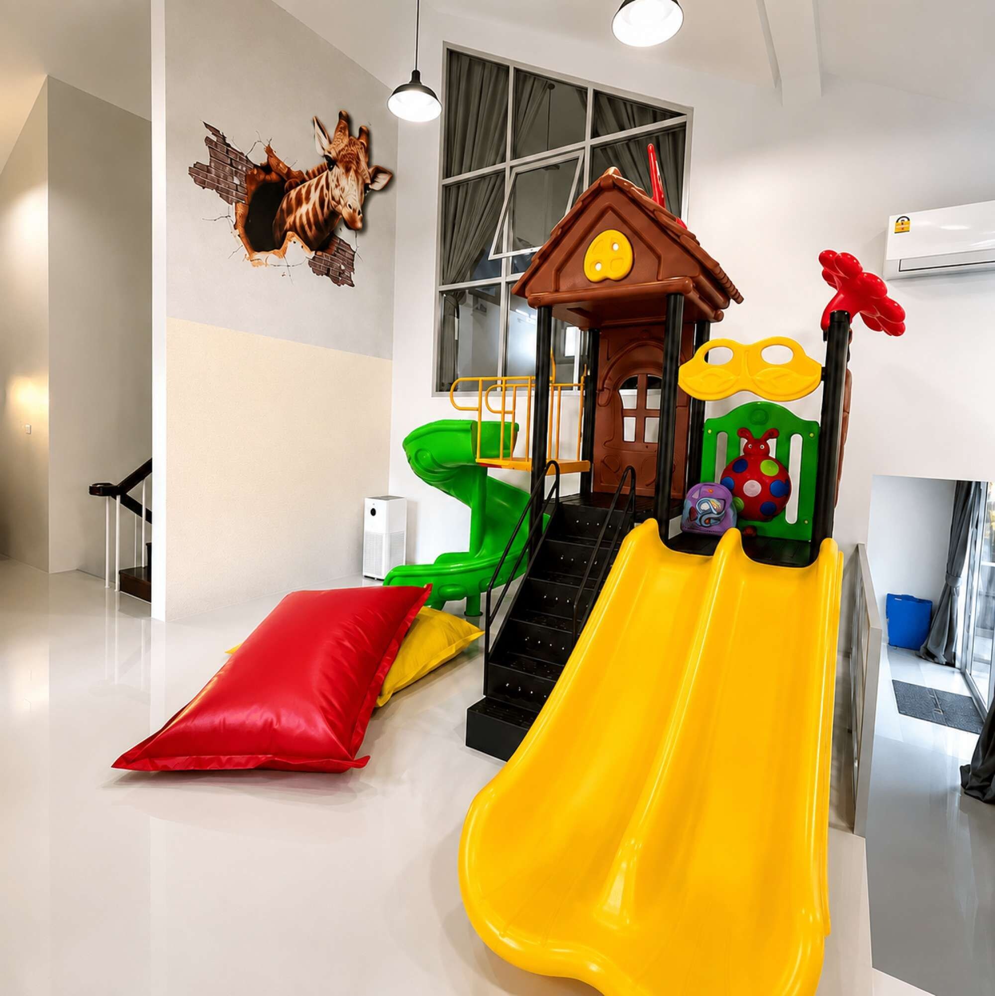 A children's play area with a slide, a climbing structure, and a small house.