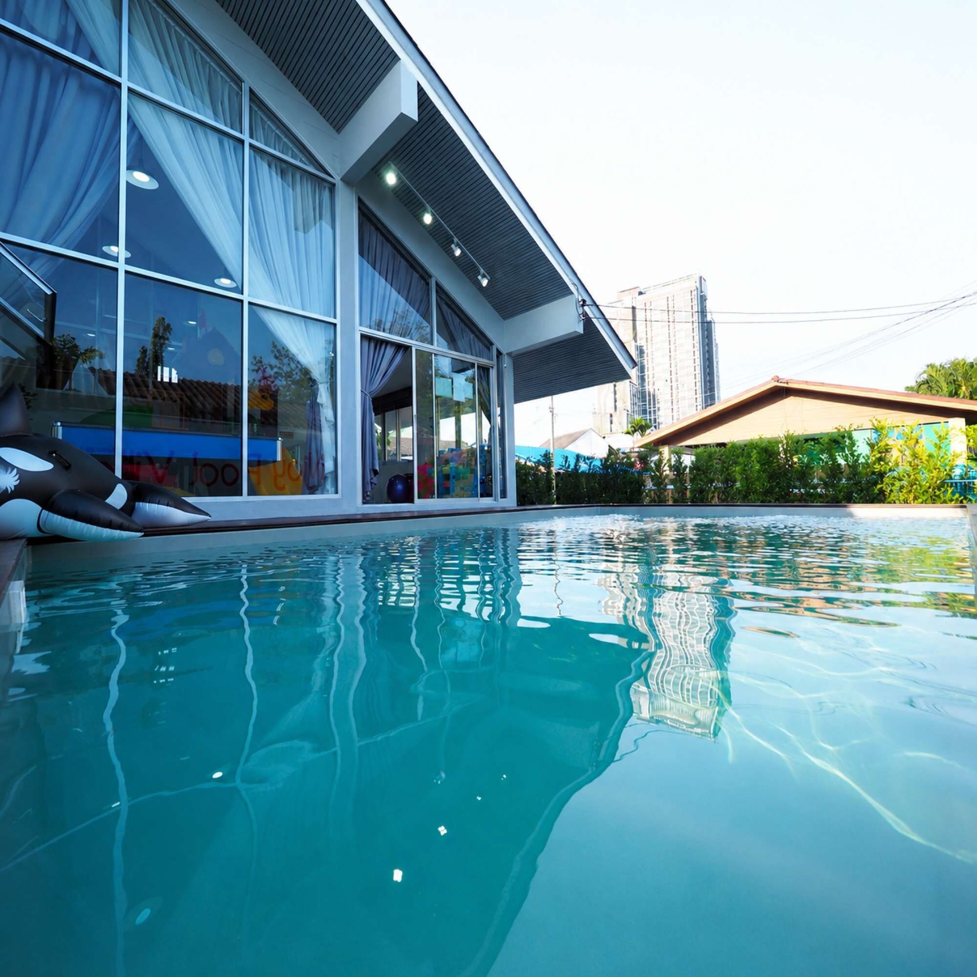 A modern building with large windows and a swimming pool in front.