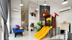 Zona de jocs interior moderna amb tobogan, casa de joc i bitlles.