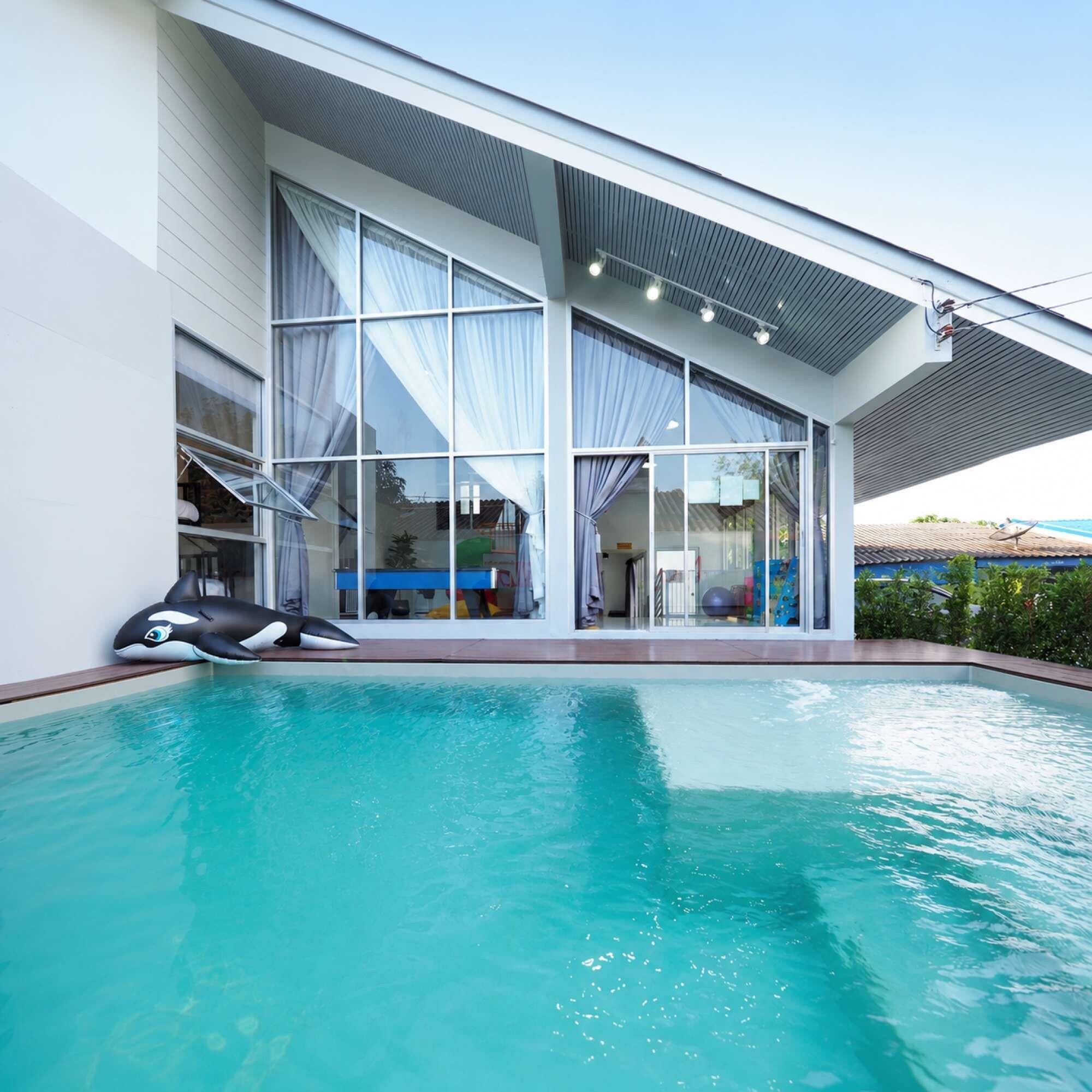 A modern house with a swimming pool, large windows, and a covered patio area.
