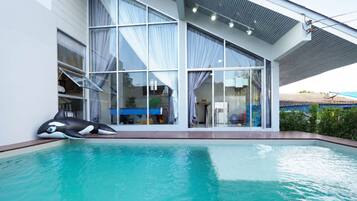 A modern house with a swimming pool, large windows, and a covered patio area.