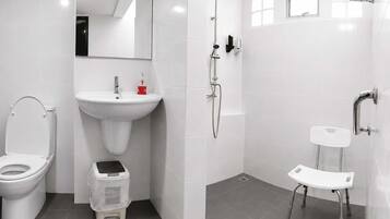 Ein modernes Badezimmer mit Toilette, Waschbecken, Dusche und einer kleinen Stehgehocker.