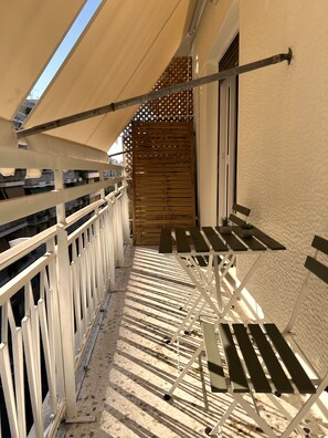 Un balcone con un cancello in legno, una ringhiera bianca e un tavolo con sedie.