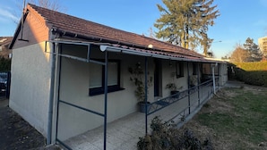 A single-story house with a tiled roof, a covered porch, and a small front yard.