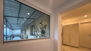 A corridor with a large window, a door, and a tiled floor.