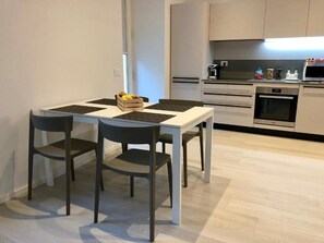 Eine moderne Küche mit Esstisch und Stühlen, einer Mikrowelle und einer Kaffeemaschine.