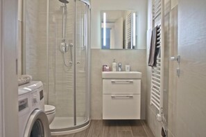 Ein Badezimmer mit Duschkabine, Toilette, Waschbecken mit Spiegel und Handtuchhalter.