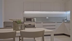 Eine moderne Küche mit weißen Schränken, einer eingebauten Mikrowelle und einer Arbeitsplatte mit Kaffeemaschine.