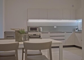 Eine moderne Küche mit weißen Schränken, einer eingebauten Mikrowelle und einer Arbeitsplatte mit Kaffeemaschine.