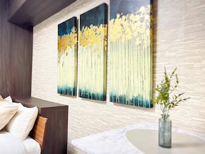 A modern room with a bed, a small table, and a wall with three vertical paintings. - Dainess Ichibankan Shibuya (Shibuya-ku)
