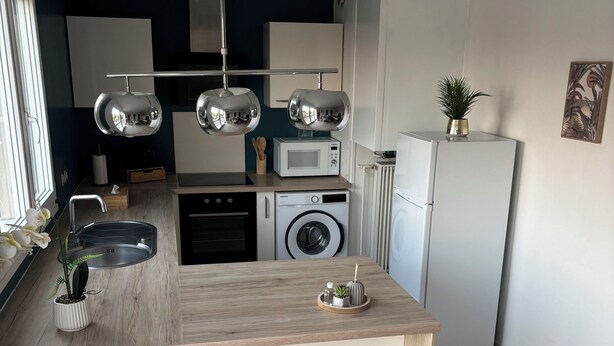 Een moderne keuken met een centraal eiland, geïntegreerde apparatuur en hanglampen.