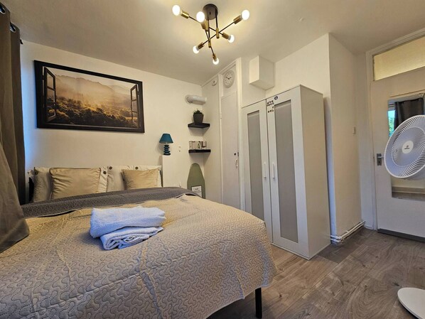 A bedroom with a bed, a wall-mounted picture, a ceiling light fixture, a wardrobe, and a fan. - Charming 2-bedroom Apartment in Deptford, Greater London, Near Greenwich (London)
