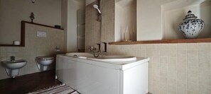 A bathroom with a bathtub, two sinks, and a shower.