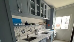 Ett modernt kök med gråa skåp, en diskho i rostfritt stål och en inbyggd tvättmaskin.