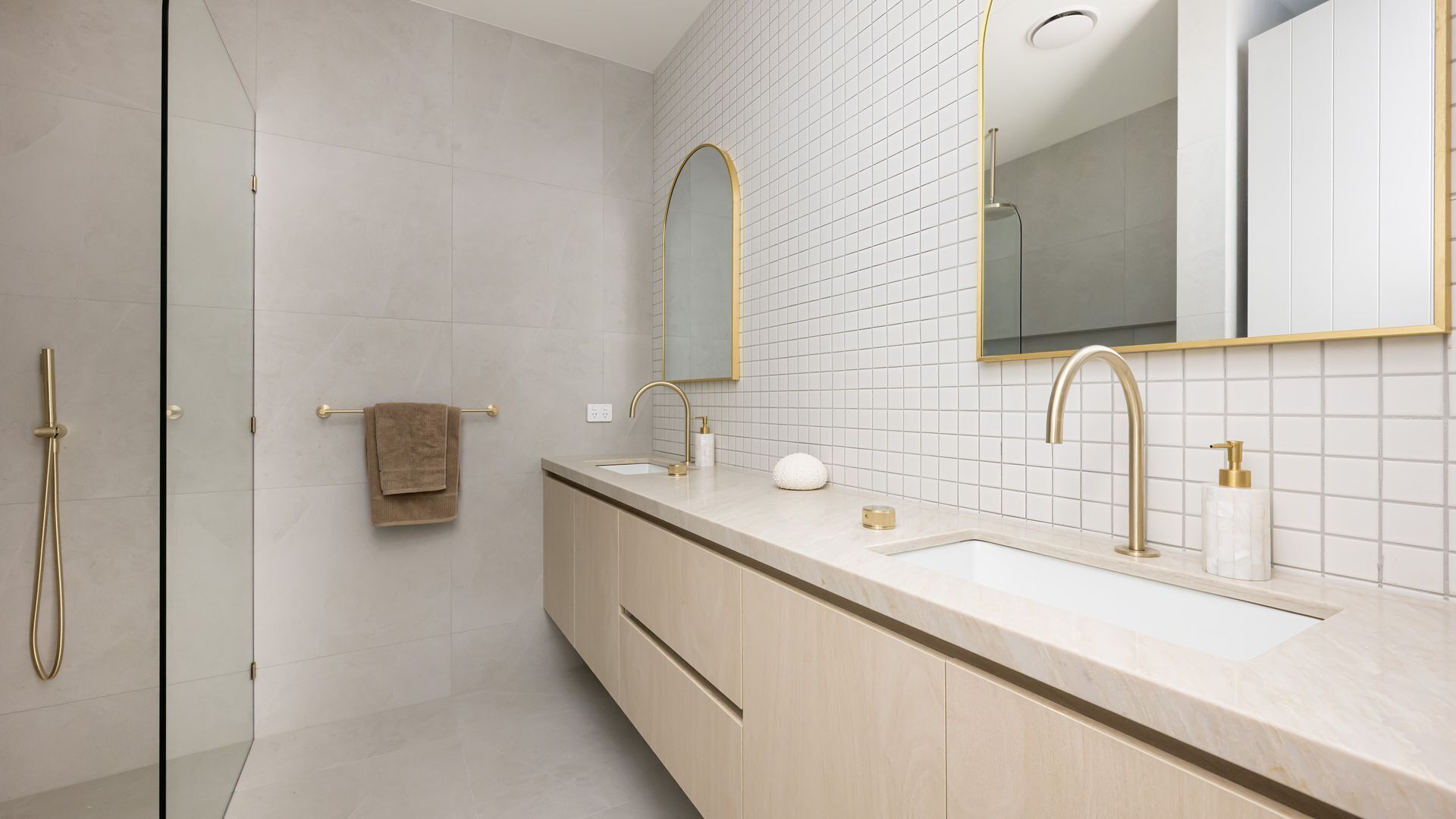A modern bathroom with a walk-in shower, a vanity with a large mirror, and a toilet.