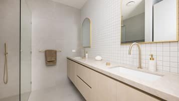 A modern bathroom with a walk-in shower, a vanity with a large mirror, and a toilet.