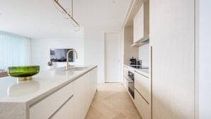 Ett modernt kök med en stor köksö, en inbyggd ugn och en stilren blandare.