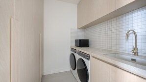 Ett kompakt kök med tvättmaskin, mikrovågsugn och en diskho med en modern blandare.