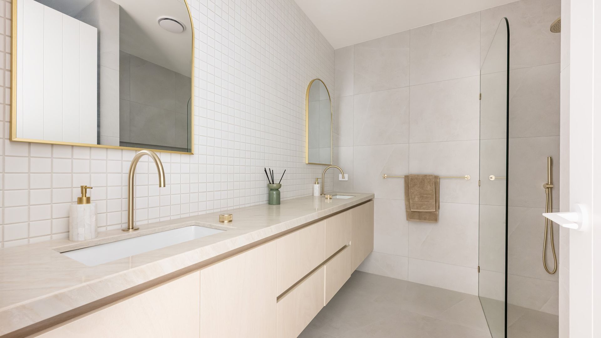 A modern bathroom with two sinks, a large mirror, and a shower.