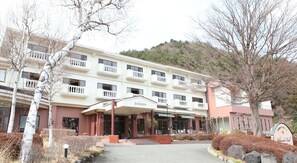 Un hotel de varios pisos con una entrada central, un área exterior cubierta y un letrero que dice "Asahidao".
