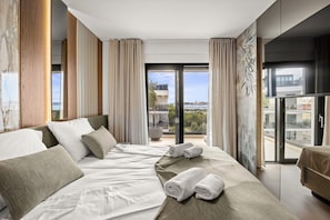 A modern hotel room with a large bed, a balcony with a view, and a seating area. - Olive Luxe Penthouse with Jacuzzi and Sea View (Zadar)