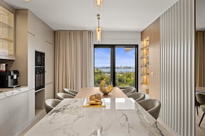 A modern kitchen with a marble countertop, a dining area with a view, and a large window. - Olive Luxe Penthouse with Jacuzzi and Sea View (Zadar)