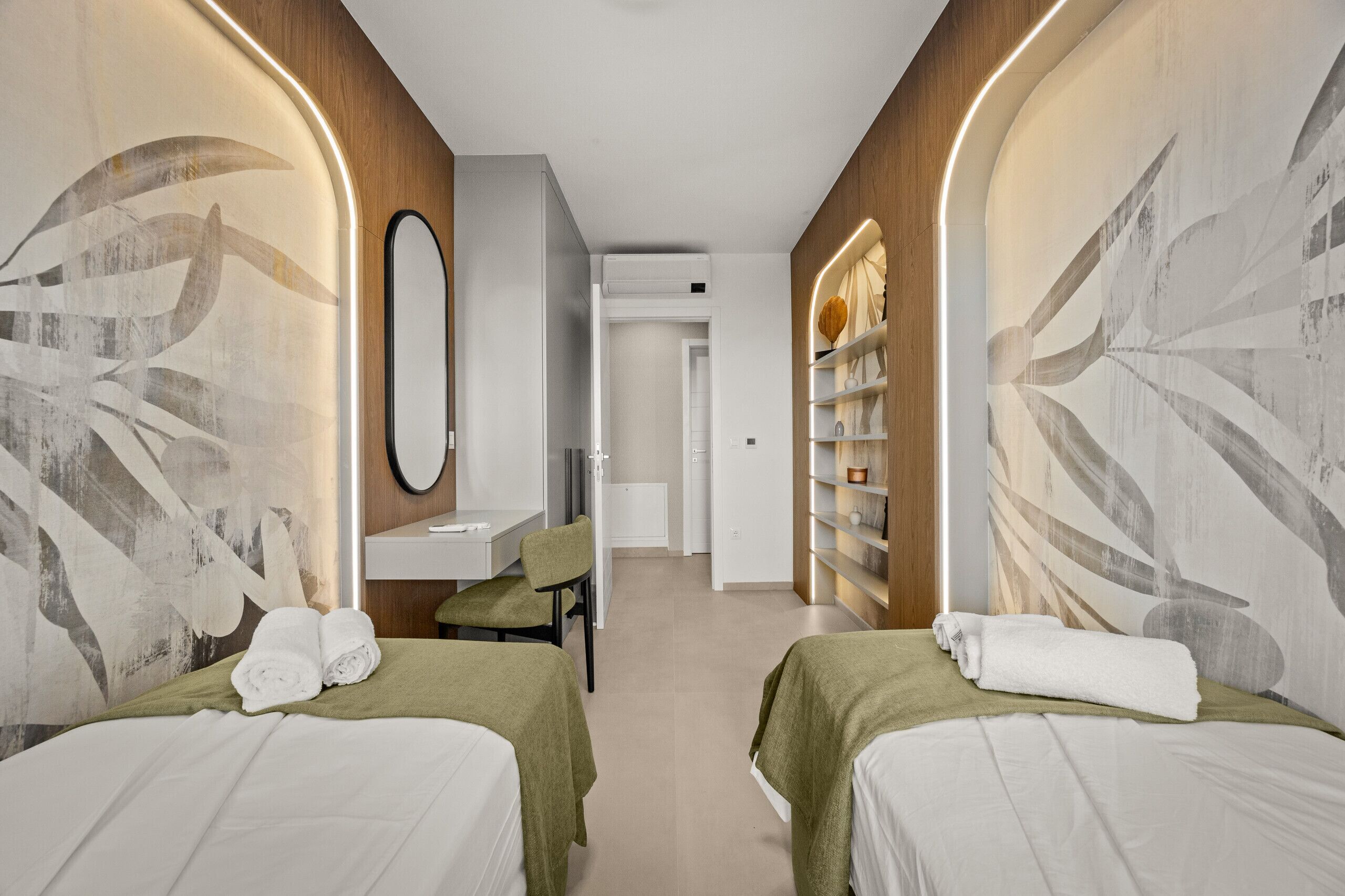 Ein Hotelzimmer mit zwei Betten, einem Schreibtisch, einem Stuhl, einem Spiegel und einem Bücherregal.