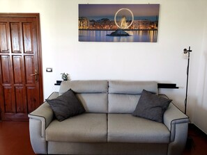 Ein Wohnzimmer mit einer Couch, einer Holztür und einem Stadtbildgemälde.