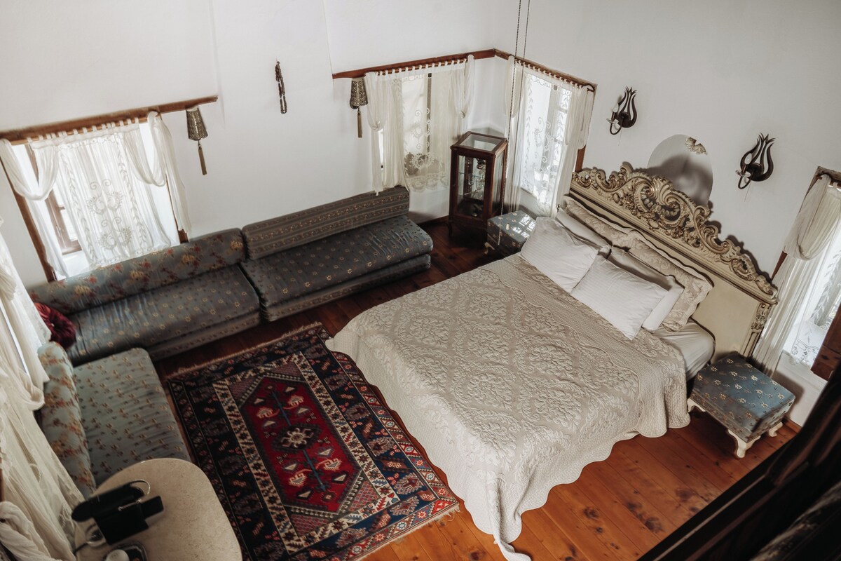 Una habitación con una cama, un sofá, una mesita y una alfombra.