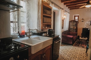 A kitchen with a stove, sink, and wooden shelves. - Boleka Bodrum (Bodrum)