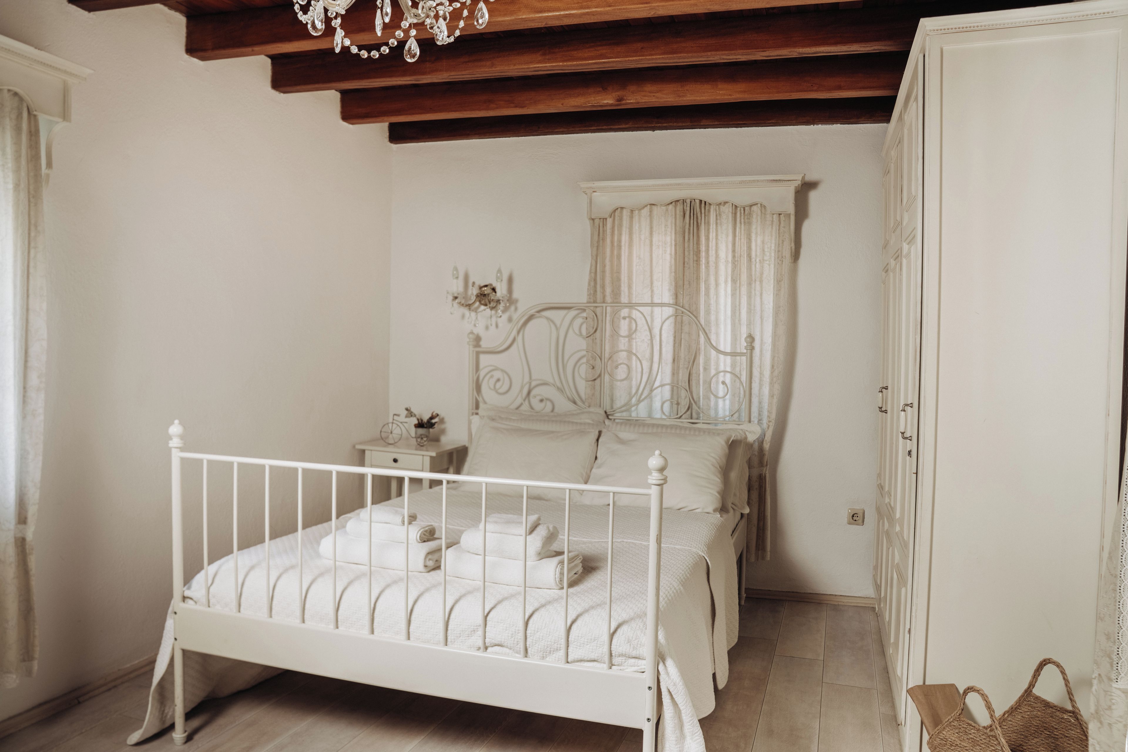 A bedroom with a white four-poster bed, a nightstand, a bedside table, and a wardrobe.