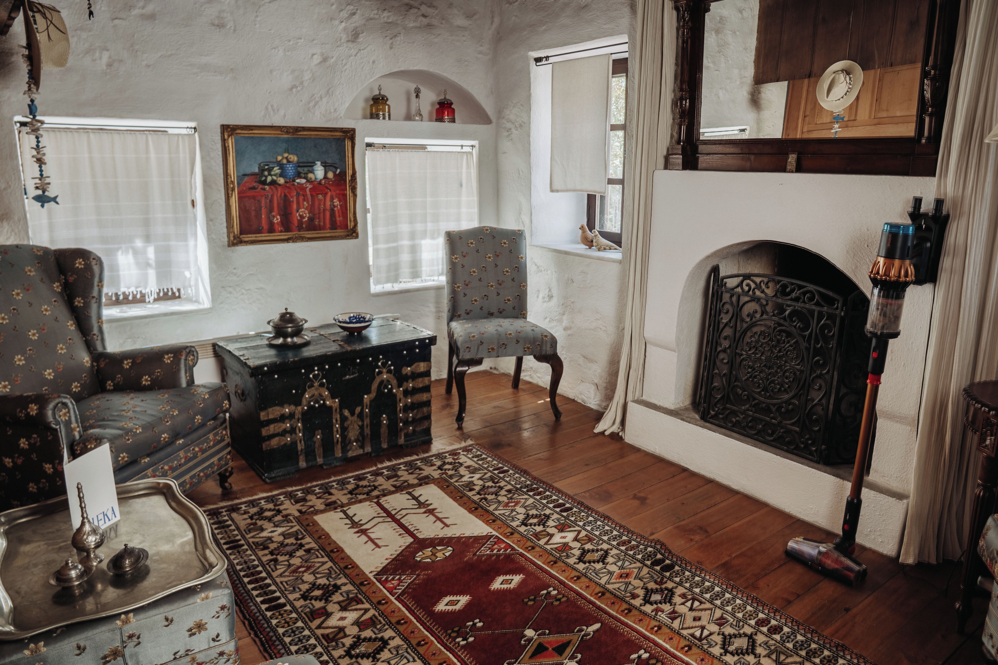 Une pièce au décor traditionnel, avec une cheminée, un tapis à motifs et un fauteuil ancien.