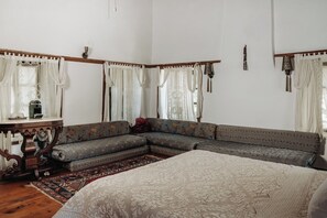 Una habitación con una cama grande, un sofá y una mesita de noche con una lámpara.