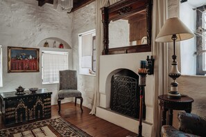 Una habitación con chimenea, una silla, una mesa con adornos y un espejo grande.