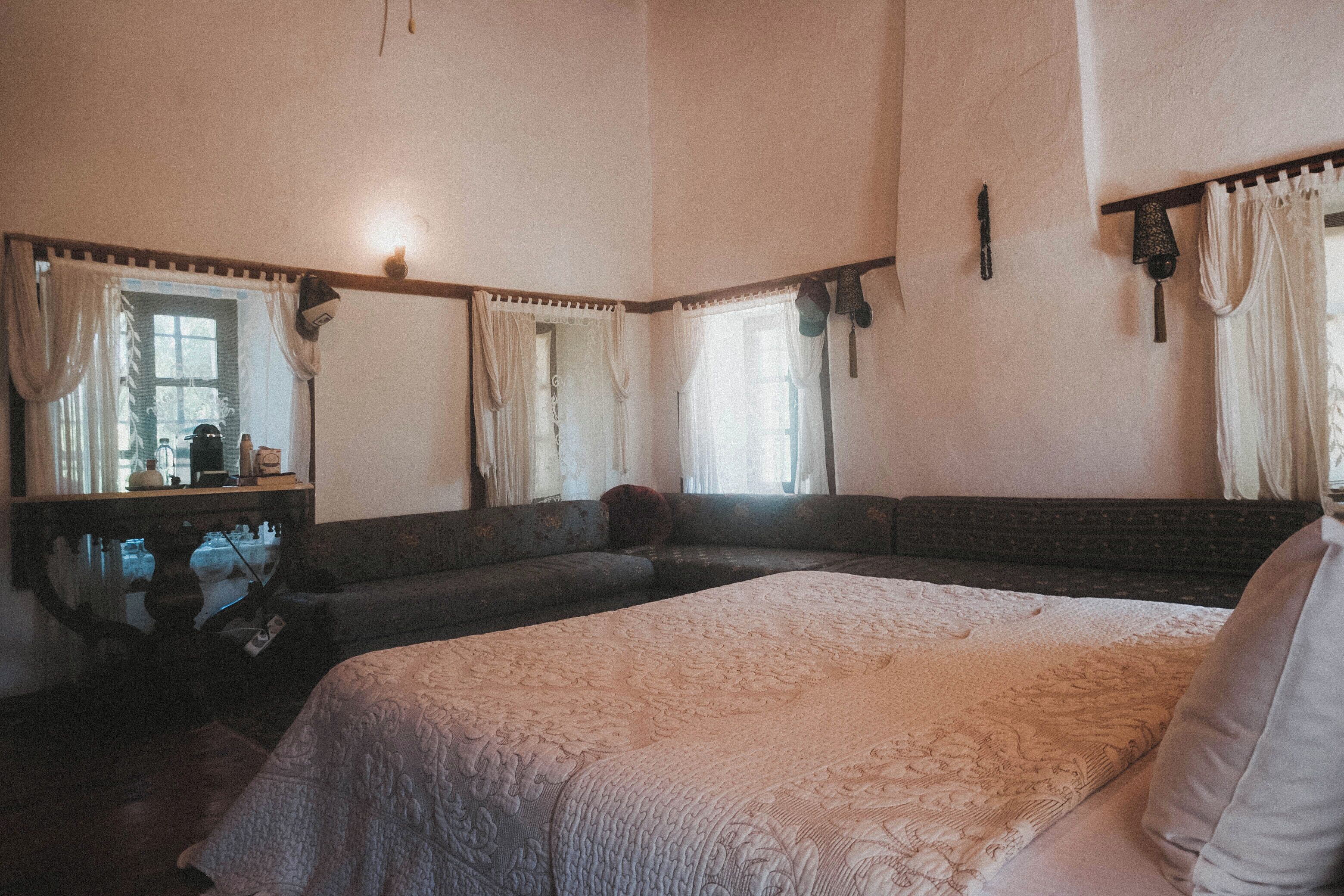 Un dormitorio con una cama grande, una mesita de noche, un aparador y una ventana con cortinas.