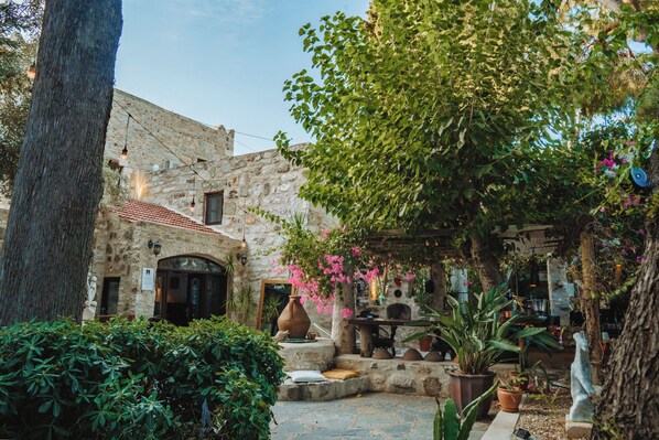 A courtyard with stone walls, a tiled roof, and potted plants.