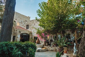 A courtyard with stone walls, a tiled roof, and potted plants.