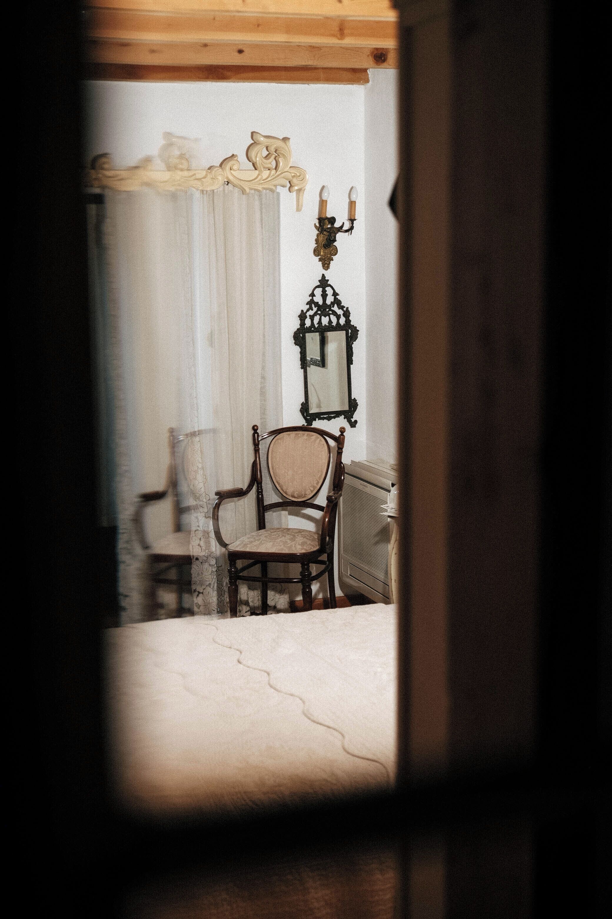 Une pièce avec une chaise en bois, un miroir et un radiateur.