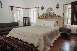 Una habitación tradicional con una cama grande, un sofá, una mesita y un adorno en la pared.