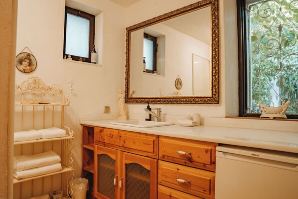 Un baño con tocador de madera, un espejo grande y una ventana con vistas a la vegetación.