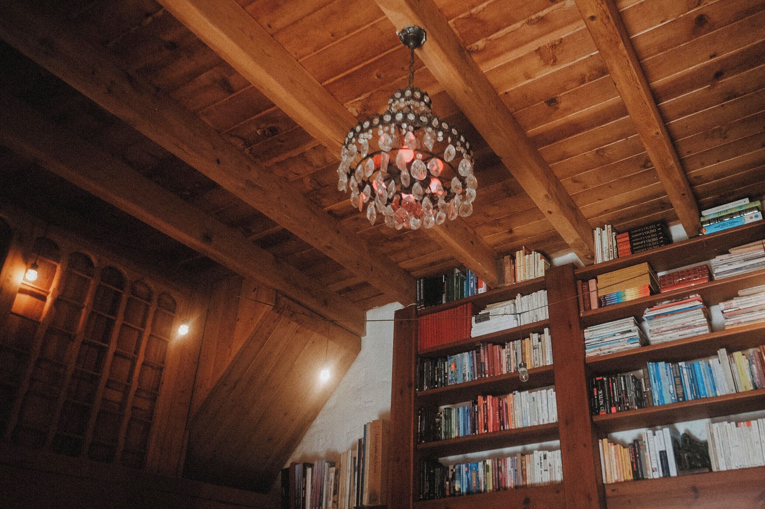 Techo de madera con candelabro de cristal y estanterías llenas de libros.