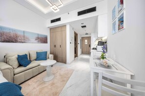 Ein modernes Wohnzimmer mit einer Couch, einem kleinen runden Tisch und einem Essbereich mit weißem Tisch und Stühlen.