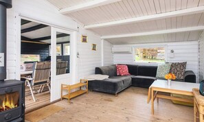 A cozy living area with a sofa, a table, a fireplace, and a window with a view. - Vacation home with ocean view—sunrise from the terrace in Denmark, 3 hours from Hamburg (Haderslev)