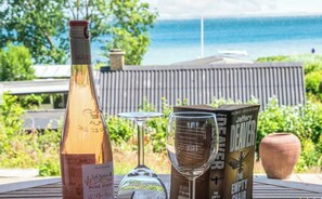 A bottle of wine, two wine glasses, and a book titled 'The Empty Chair' on a table with a view of the ocean. - Vacation home with ocean view—sunrise from the terrace in Denmark, 3 hours from Hamburg (Haderslev)