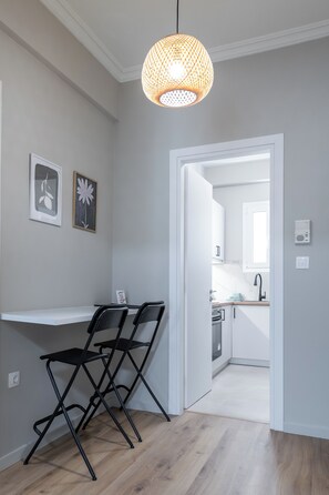 A modern kitchen with white cabinets, a black faucet, and a wooden countertop. - Charming 2BR Downtown Metro (Athina)