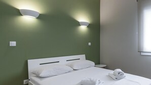 Habitación de hotel con cama, dos lámparas fijadas a la pared, una ventana y una mesita redonda.